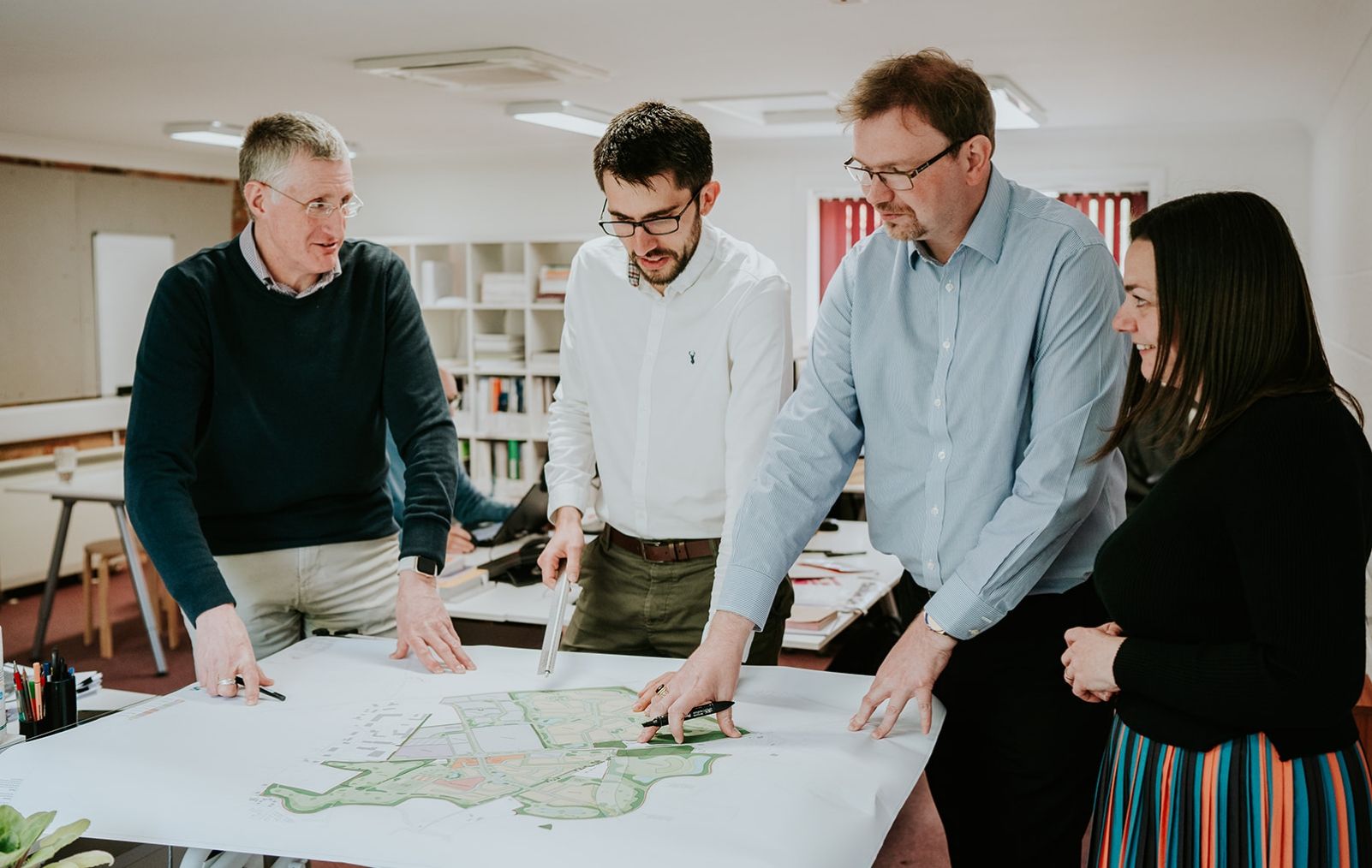 A group of people stood around a table with a land plan